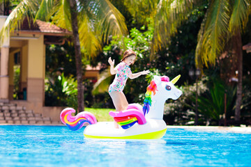 Wall Mural - Child on unicorn float in swimming pool. Kids swim