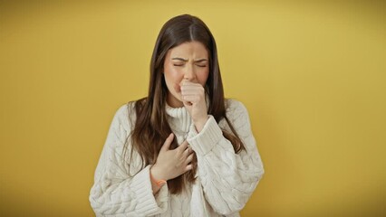 Poster - Beautiful young hispanic woman, coughing and feeling unwell in yellow sweater over isolated background - sign of cold or bronchitis, urgent need for health care