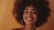 © Ahmed - Carefree woman with Afro hair smiling at the camera while standing against a studio background. Beautiful young woman of colour wearing her natural hair with pride