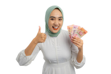 Wall Mural - Cheerful young Asian woman in green hijab and white blouse holding money and giving thumbs up isolated on white background
