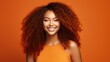 © ALA - Beautiful, sexy, happy smiling dark-skinned African American woman with perfect skin and red hair, on an orange background, banner.