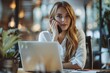 © Sandu - Woman at table using laptop and speaking on cellphone