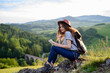 © Halfpoint - Young tourist woman traveller with backpack in nature, sitting and resting. Active hiker on trail in mountains enjoying breathtaking view.