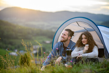 Wall Mural - travellers couple spending time outdoor, sleeping in tent shelter. young tourist sitting in nature, 