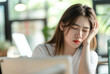 © Kritchanok - a woman holding her head on a computer at the office , stress from working