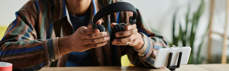 Wall Mural - A young African American male blogger is creatively engaging with a headset on a table.