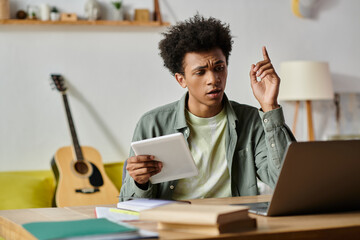 Wall Mural - A man, immersed in online study, sits at a table with a laptop open in front of him.