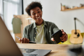 Wall Mural - A man working at a desk with a laptop and cell phone.