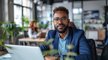 Poster - young african american businessman in eyeglasses using laptop in office