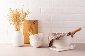 Wall Mural - Set of white ceramic bowls for cooking on a stone kitchen countertop. a white vase with ears of wheat. A white brick wall. minimalism.