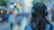 © May Chanikran - Person wearing headphones walking in a busy, blurred city street. Urban lifestyle, music, solitude, and modern living concept image.