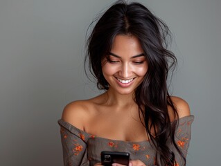 Wall Mural -  south asian woman sitting on studio looking down at her phone and smiling, studio environment