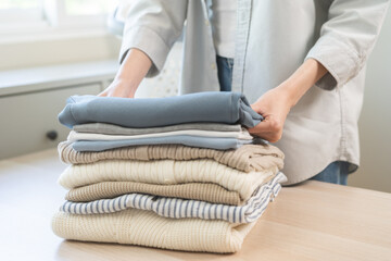 Wall Mural - Feel softness, chore of asian young woman, girl housewife hand folding clean clothes after washing, laundry and dry, holding pile, stack clothing from table working at home. Laundry maid in household.