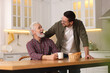 © New Africa - Happy son and his dad at wooden table in kitchen