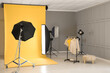 © New Africa - Yellow photo background, rack with clothes and professional lighting equipment in modern studio