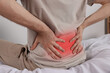 © New Africa - Man suffering from pain in lower back indoors, closeup