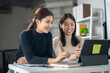 © Wasana - Two women are sitting at a desk looking at a laptop