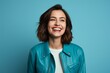 © CogniLens - Portrait of a grinning woman in her 30s wearing a trendy bomber jacket on soft blue background
