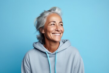 Wall Mural - Portrait of a satisfied woman in her 50s sporting a comfortable hoodie on soft blue background