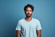 © CogniLens - Portrait of a glad indian man in his 20s donning a trendy cropped top over soft blue background