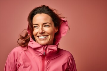 Canvas Print - Portrait of a grinning woman in her 40s wearing a windproof softshell in front of soft pink background