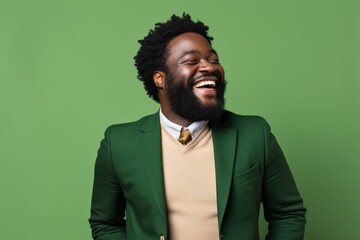 Wall Mural - Portrait of a grinning afro-american man in his 30s dressed in a stylish blazer on soft green background