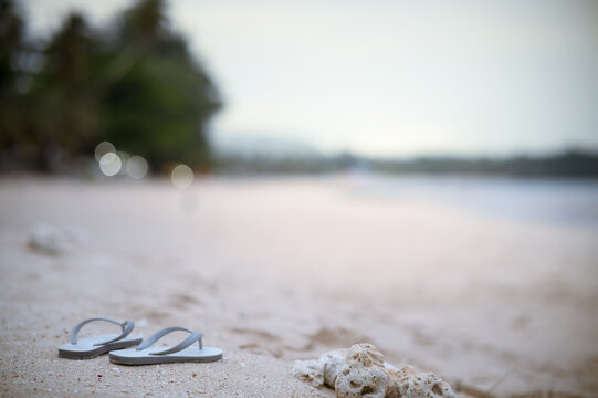 A pair of sandals on the sand. The background is blurred, emphasizing the sandals in the foreground. and create a calm and relaxing atmosphere.