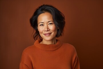 Poster - Portrait of a content asian woman in her 40s wearing a cozy sweater in soft brown background