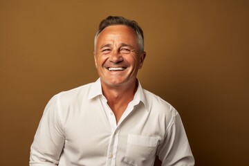 Poster - Portrait of a cheerful man in his 50s wearing a classic white shirt on soft brown background