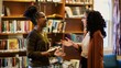 © Felippe Lopes - Two women having an engaging conversation in a library, surrounded by shelves filled with books.