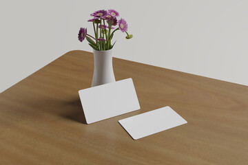 Realistic mockup of two business cards lying in front of a flower vase and on a wooden table