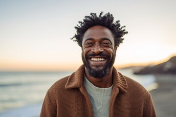 Portrait of a joyful afro-american man in his 40s dressed in a warm wool sweater on stunning sunset beach background
