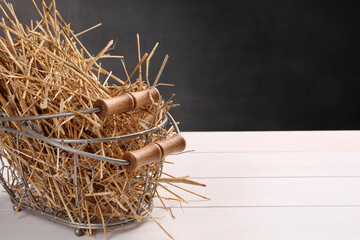 Poster - Dried straw in metal basket on white wooden table, space for text