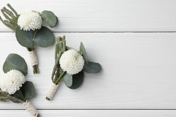 Sticker - Small stylish boutonnieres on white wooden table, flat lay. Space for text