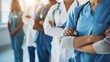 © mashimara - Close-up of a doctor in blue scrubs with a stethoscope, with a medical team in the background. Ideal for healthcare, teamwork, and medical professionalism concepts.