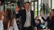 © Naeem - A cheerful businessman walking through a busy office, high-fiving team members as he passes by, exuding energy and enthusiasm.