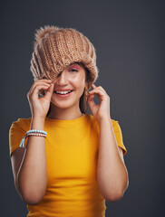 Studio portrait, girl and beanie with happiness for autumn or winter fashion, accessory and style with mockup. Female student, smile and teenager with wool hat for cold weather by dark background