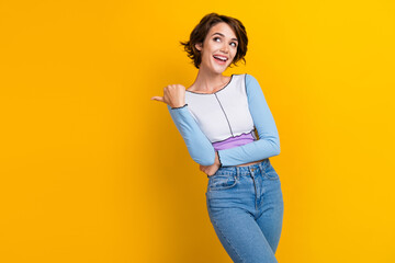 Wall Mural - Photo of impressed funky lady dressed shirt looking pointing thumb empty space isolated yellow color background