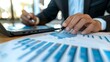 © BrilliantPixels - Close-up of Hand Analyzing Business Charts with Pen