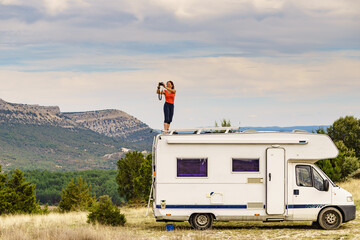 woman traveling with caravan, taking photo from rv roof