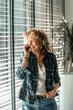 © Ed - Business concept portrait of a business woman 45 years old with a smile on her face talking on the phone, standing in half profile leaning against the window, casual elegant clothes