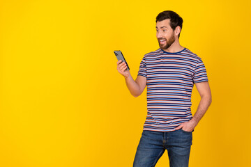 Poster - Portrait of overjoyed guy with bristle wear striped t-shirt look at smartphone read email isolated on vivid yellow color background
