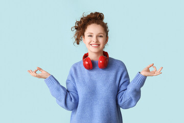 Portrait of relaxed young woman with headphones meditating on blue background