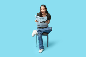 Poster - Happy young woman with newspaper on blue background