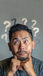 © Mrt - Portrait of an asian man with a puzzled, thoughtful expression, surrounded by question marks, capturing moments of uncertainty and contemplation, copy space for text.