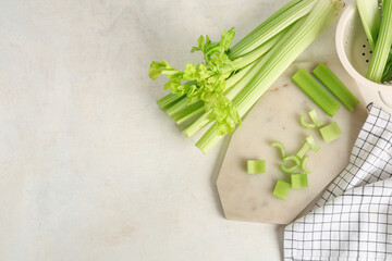 Wall Mural - Board and colander with fresh green celery on white background
