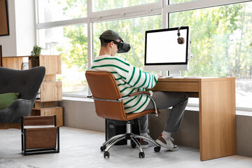 Canvas Print - Young man in VR glasses using computer at home