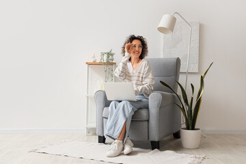 Sticker - Mature woman using laptop in grey armchair at home