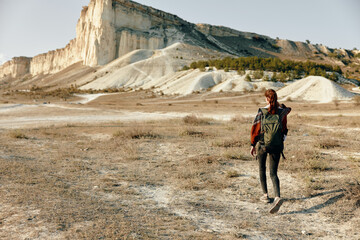 Wall Mural - solitary hiker trekking through arid desert landscape with towering mountain peak in the distance