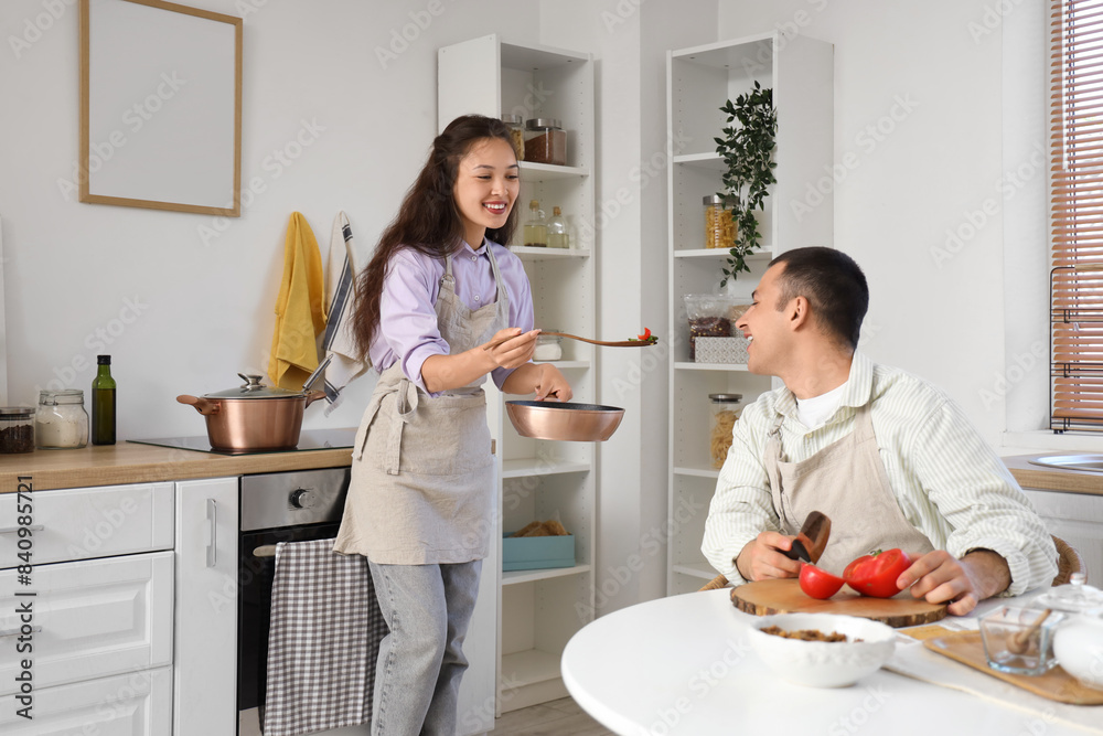 Young couple tasting soup in kitchen